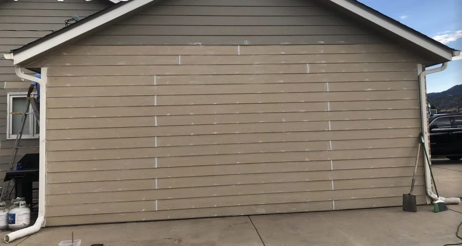Gable end of a house re-sided in lap siding, the patched boards still unpainted
